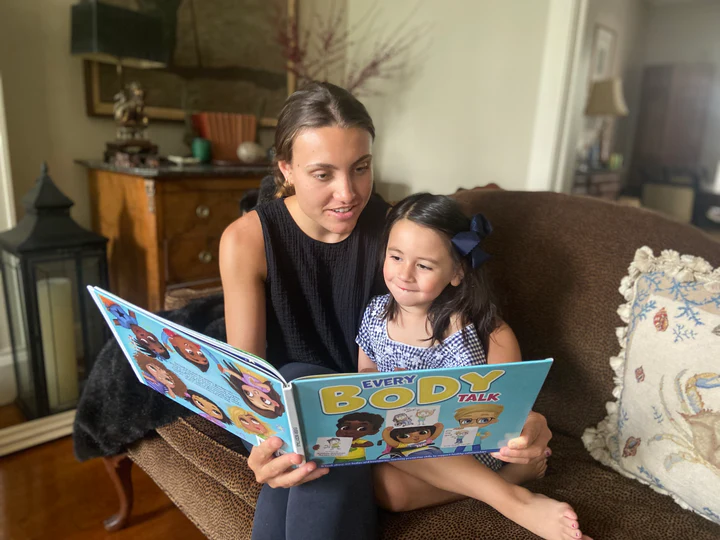 A young mom reading the Every Body Talk book to her daughter